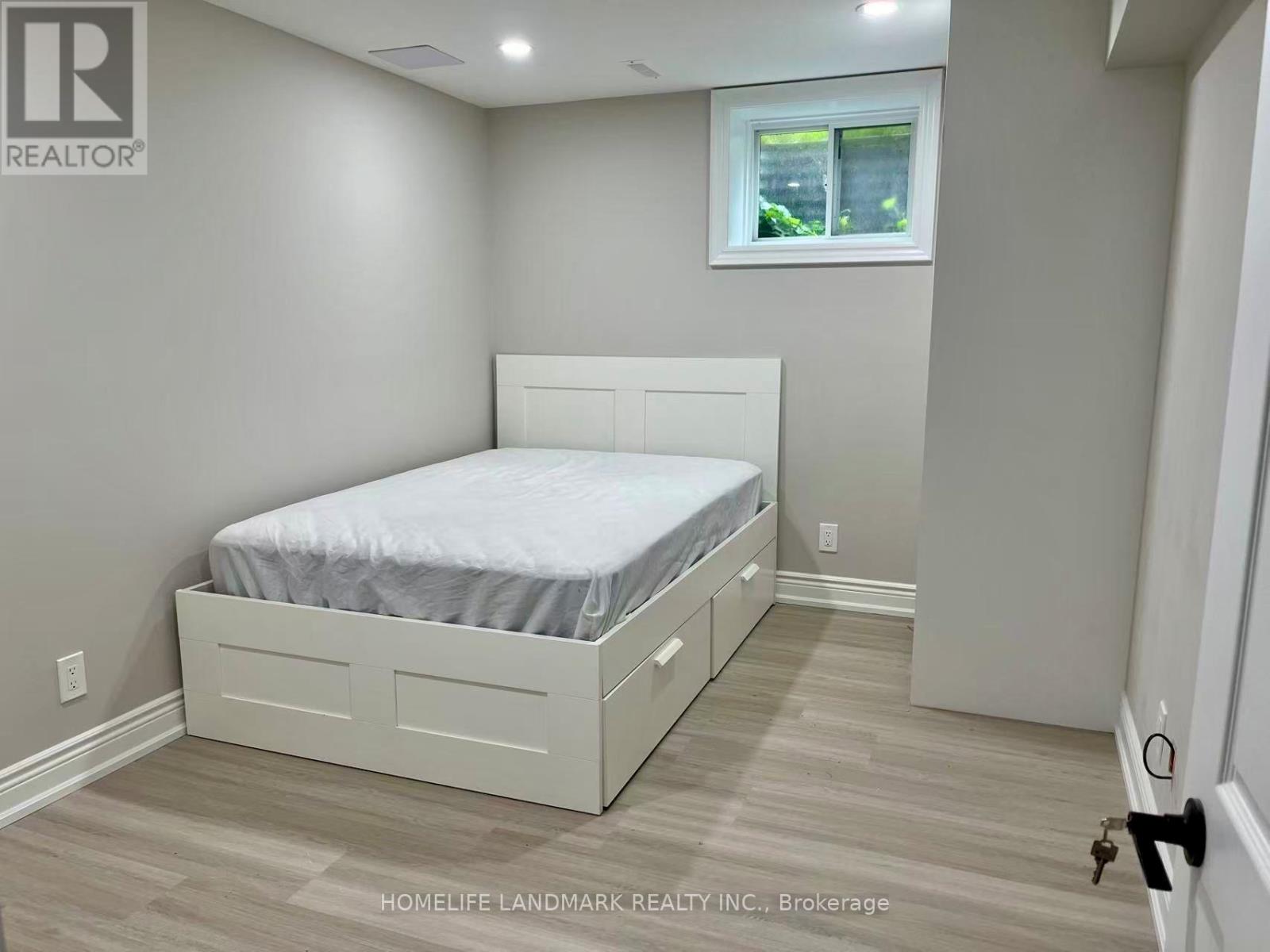 A bedroom with a bed, nightstand, and window.