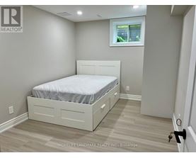 A bedroom with a bed, nightstand, and window.
