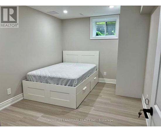 A bedroom with a bed, nightstand, and window.
