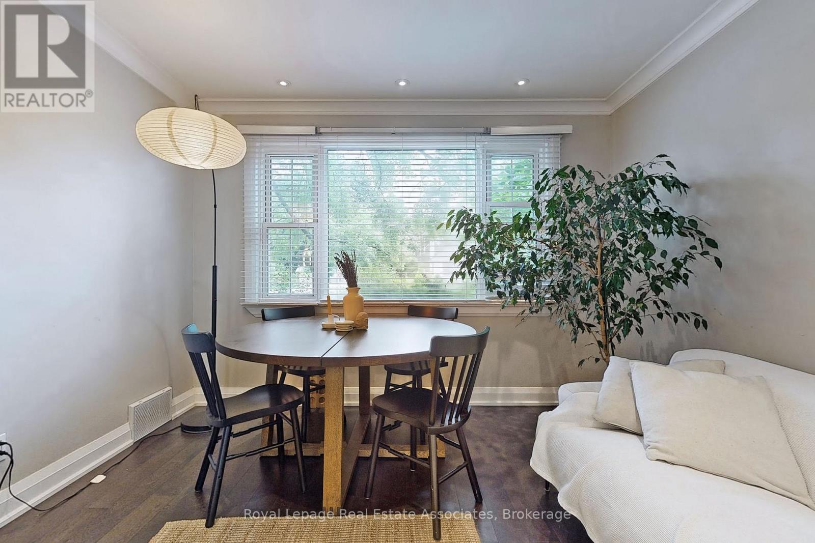A dining room with a table, chairs, and a plant.