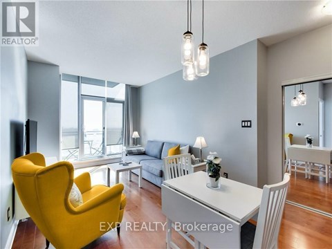 A living room with a yellow chair and a white dining table.