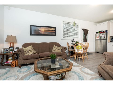 A living room with a brown couch, a coffee table, and a painting on the wall.