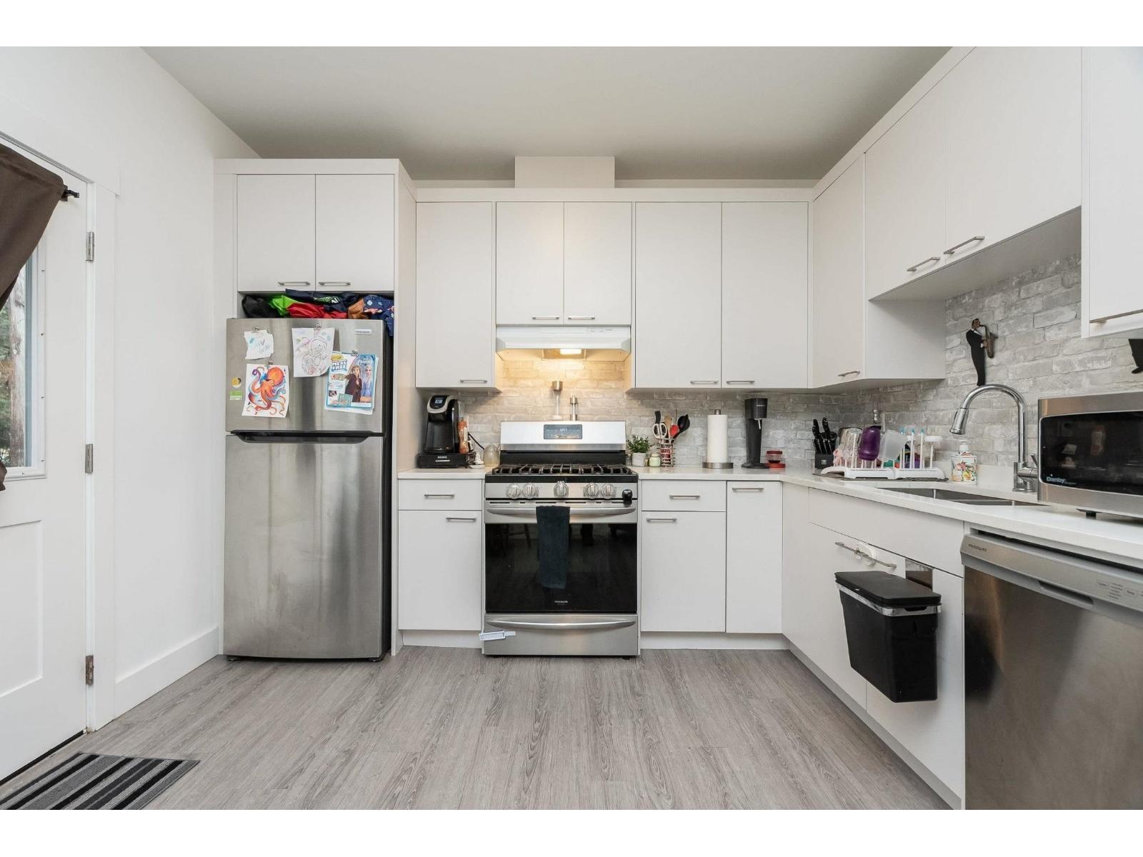 A kitchen with white cabinets and a fridge with magnets on it.