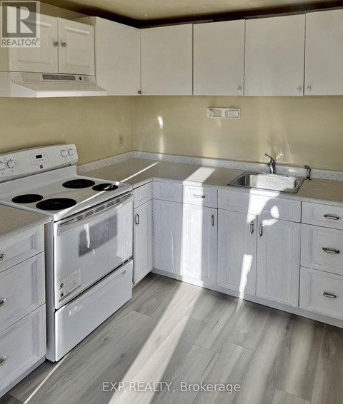 A kitchen with white cabinets and a stove top oven.