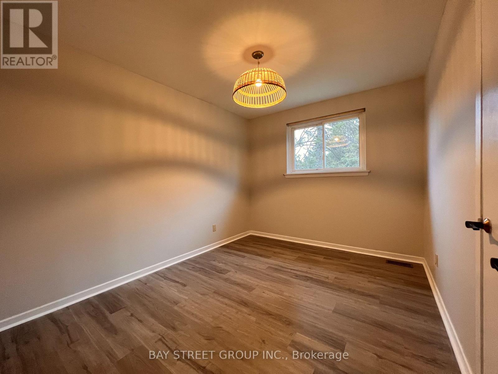 A room with a wooden floor and a window with a view of trees.
