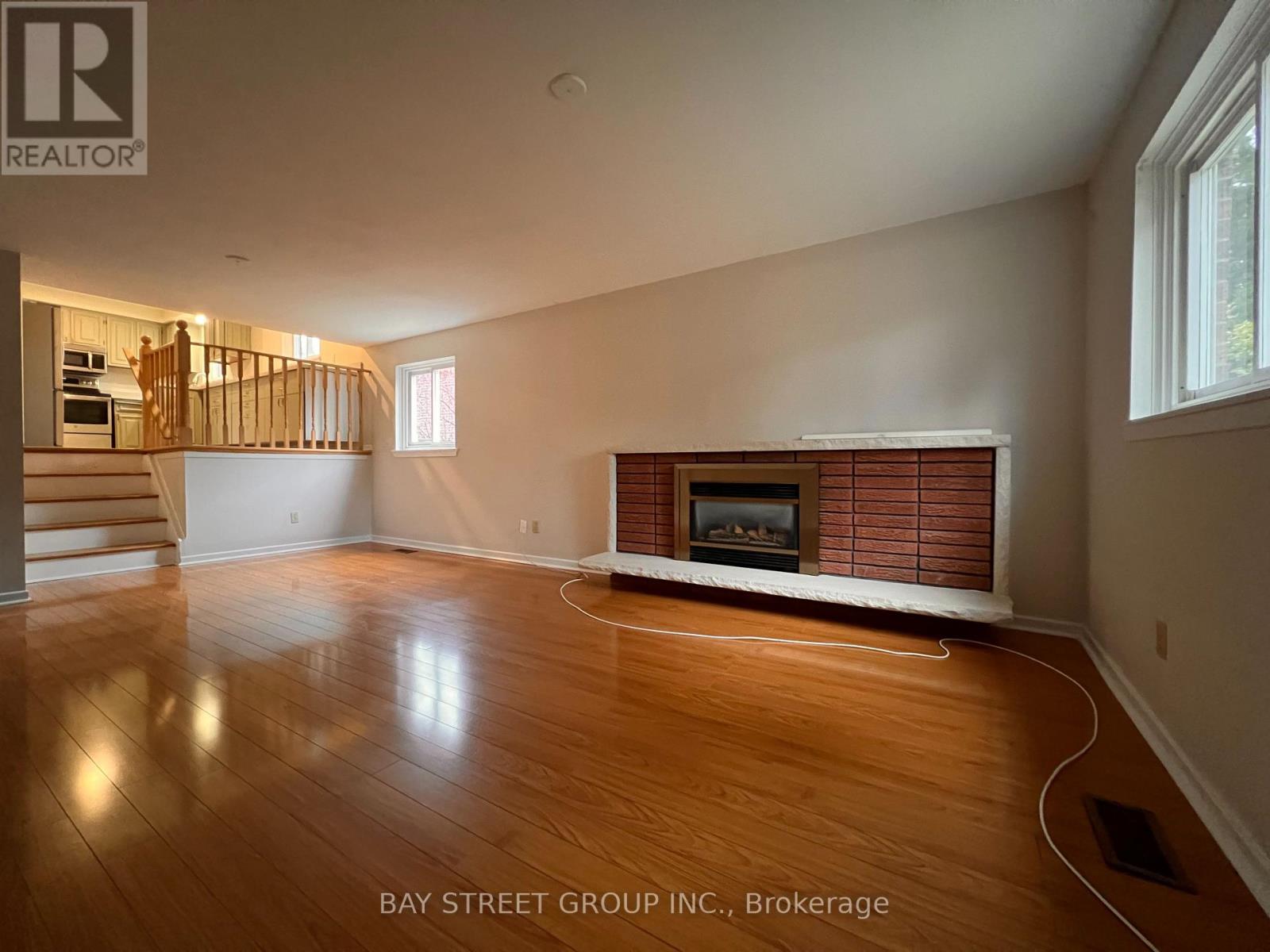 A spacious living room with a fireplace and wooden floors.