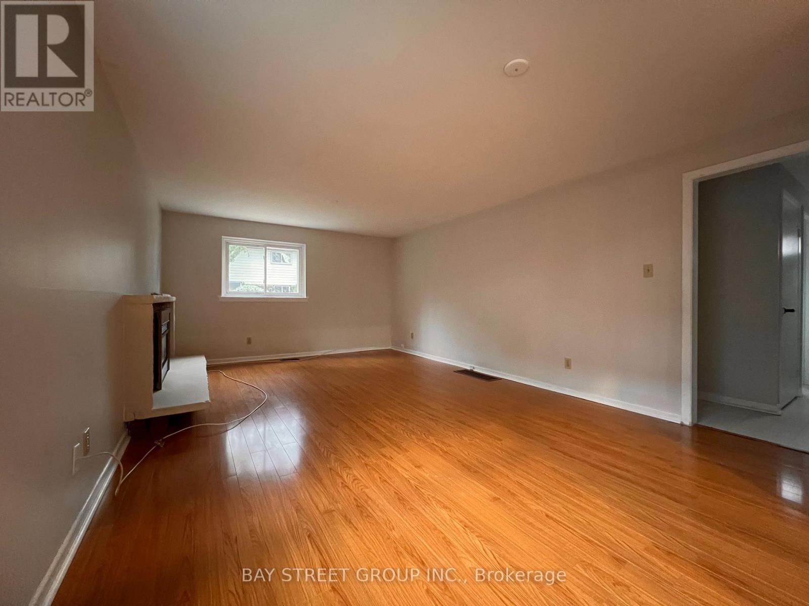 A spacious room with wooden floors and a window.