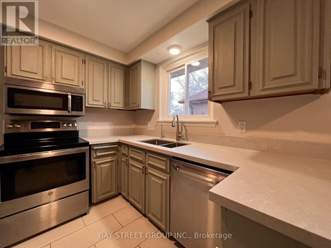 A kitchen with a stove top oven and microwave, sink and cabinets.