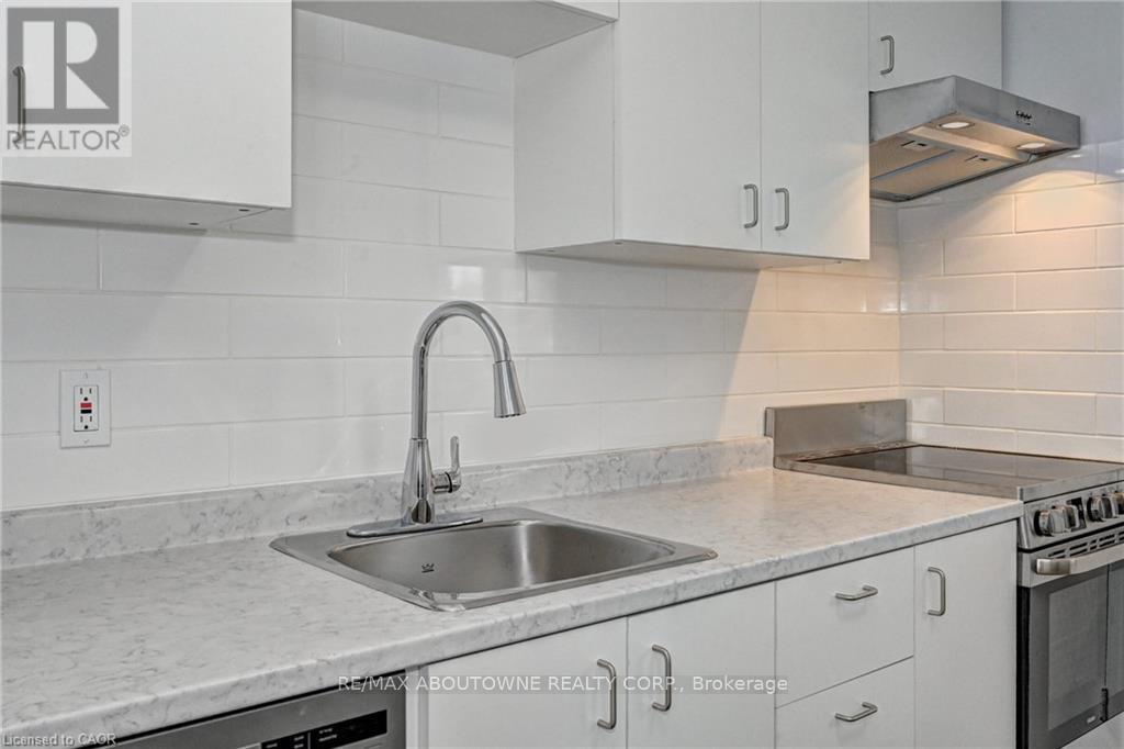 A modern kitchen with a stainless steel sink and white cabinets.