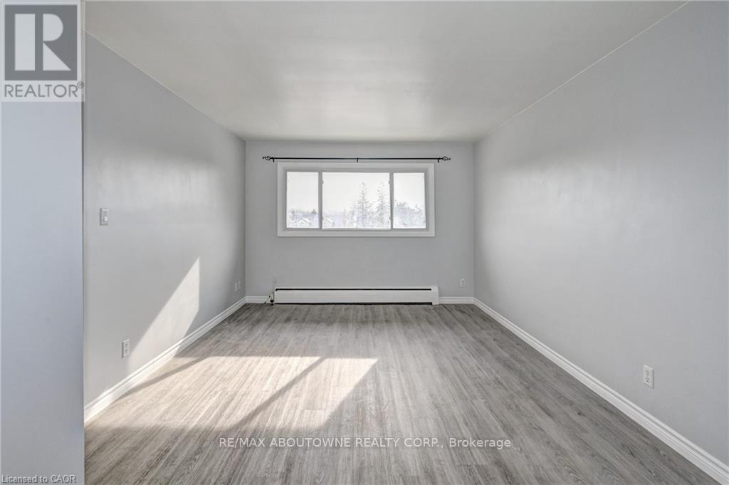 A spacious room with a window and wooden flooring.