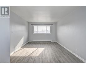A spacious room with a window and wooden flooring.