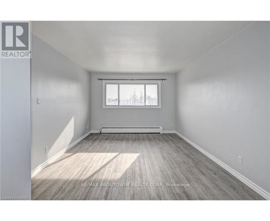 A spacious room with a window and wooden flooring.