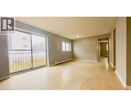 A spacious room with a sliding glass door leading to a balcony.