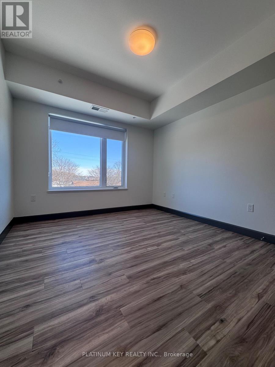A room with wooden flooring and a window showing a view of trees.