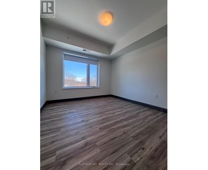 A room with wooden flooring and a window showing a view of trees.