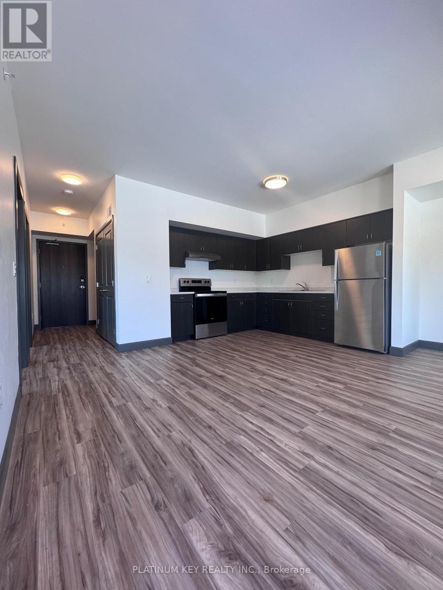 A modern kitchen with dark wood flooring and stainless steel appliances.