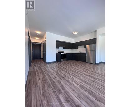 A modern kitchen with dark wood flooring and stainless steel appliances.