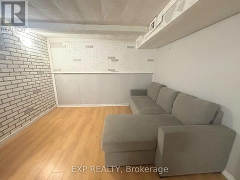 A living room with a grey couch and a brick wall.