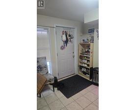 A room with a door, a shoe rack and a mat on the floor.