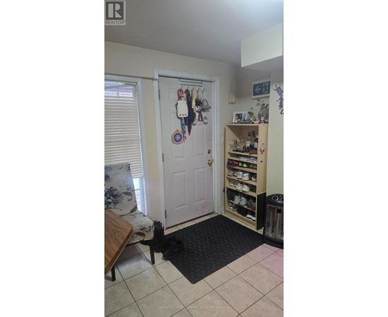 A room with a door, a shoe rack and a mat on the floor.