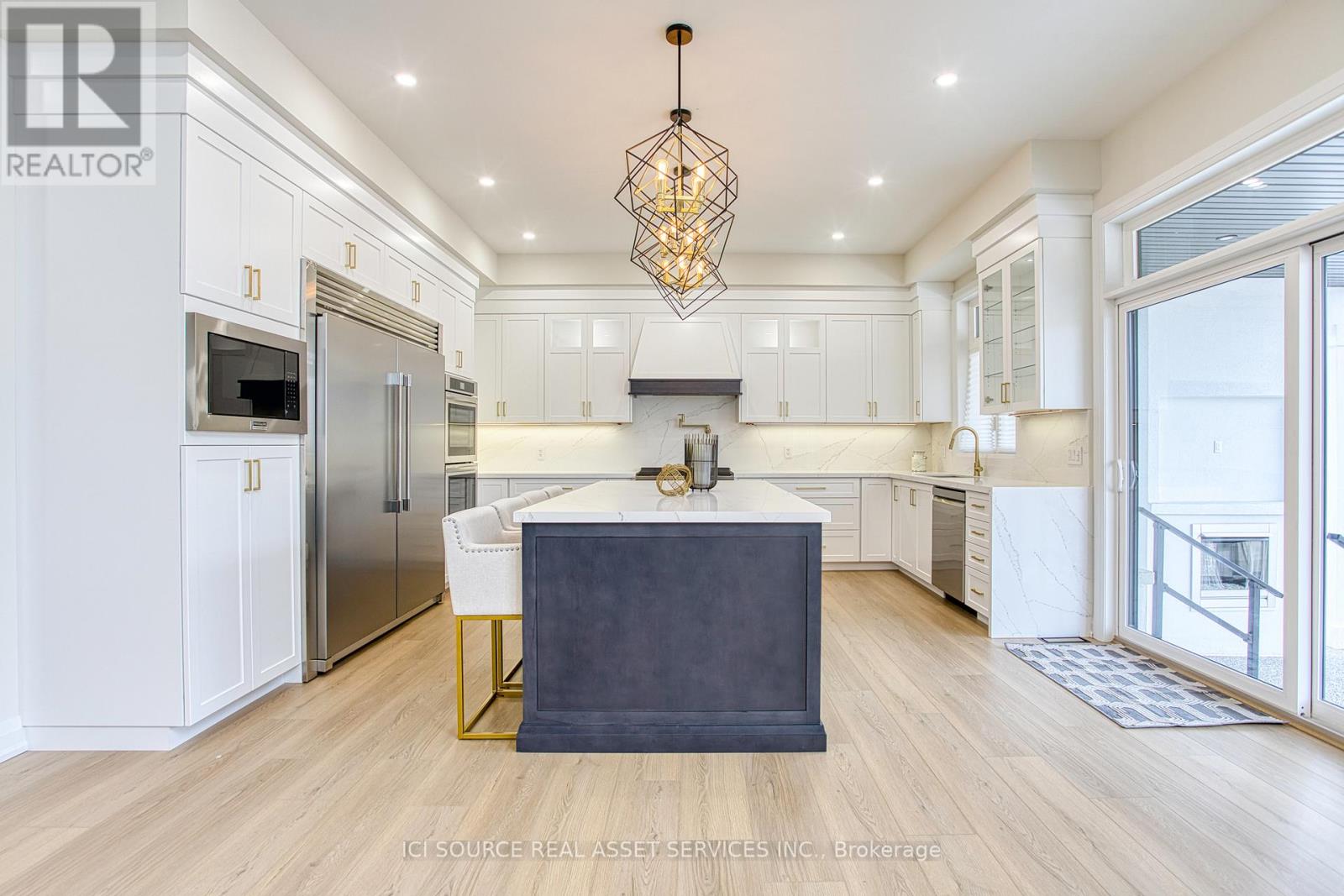 A modern kitchen with a central island and a refrigerator to the left.