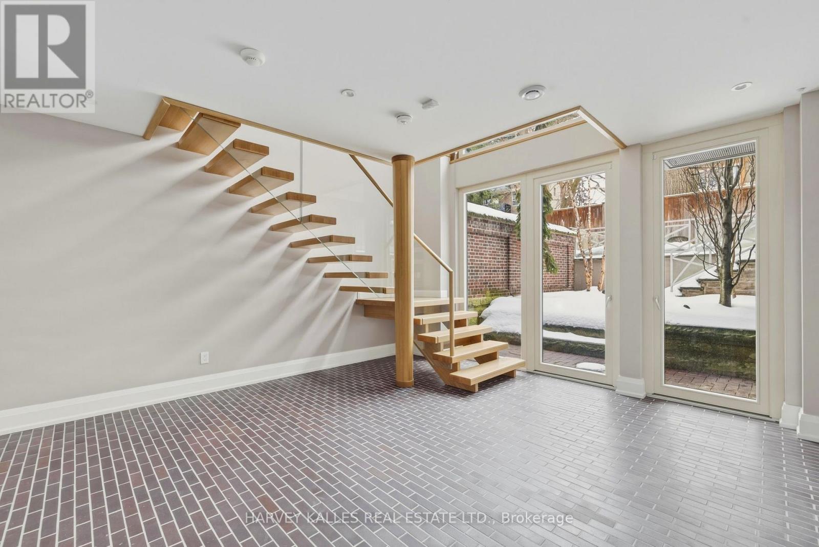 A spacious room with a wooden staircase and tiled flooring.
