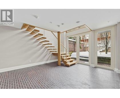 A spacious room with a wooden staircase and tiled flooring.