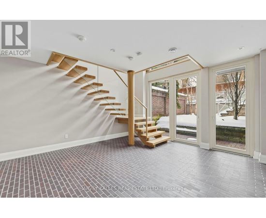A spacious room with a wooden staircase and tiled flooring.