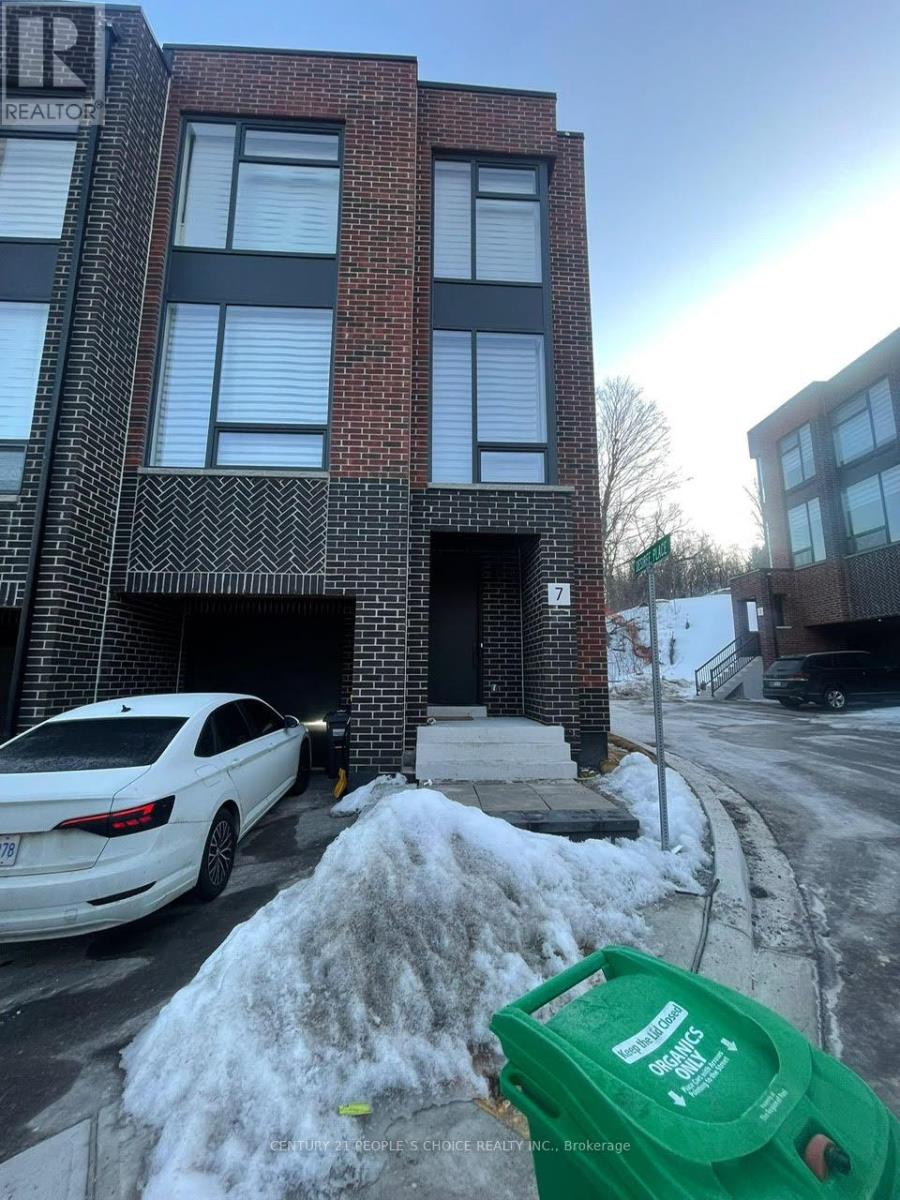 A white car is parked in front of a brick building.