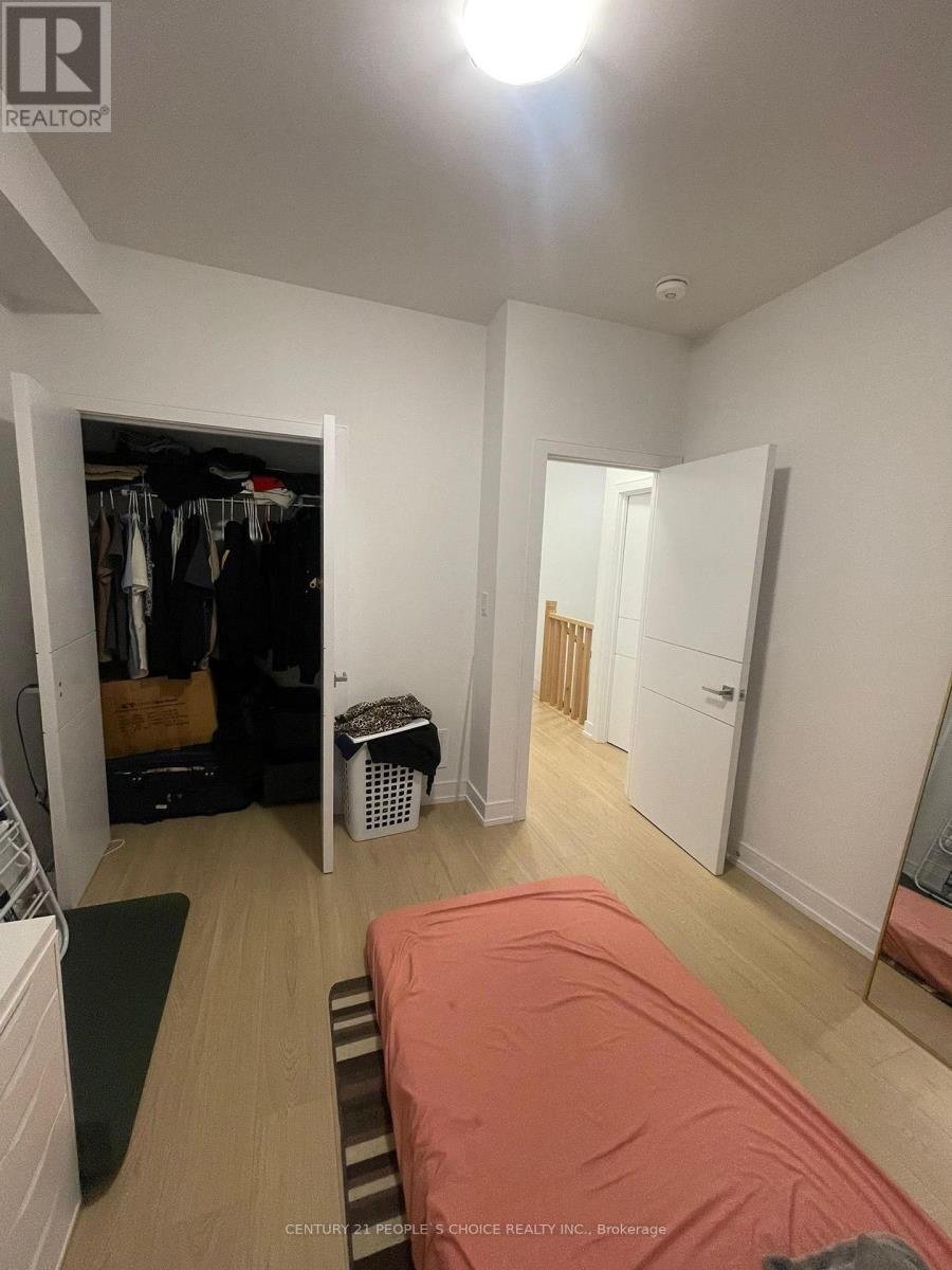 A bedroom with a bed covered in a red sheet and a wardrobe with clothes in it.