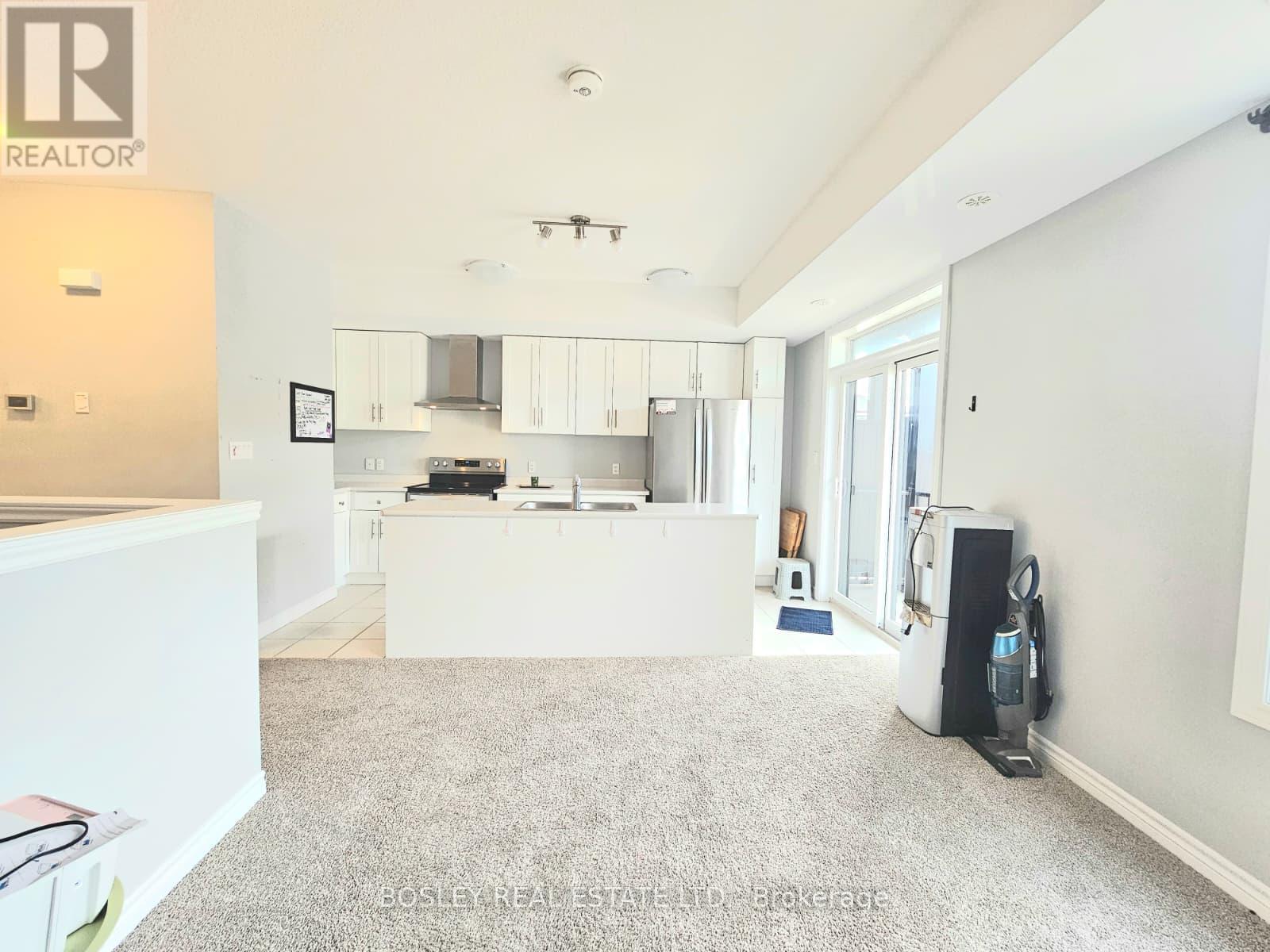A spacious living room with a kitchen in the background.