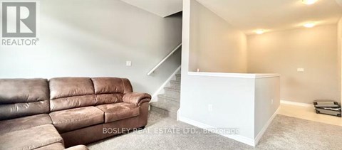A living room with a brown leather couch and a white staircase.