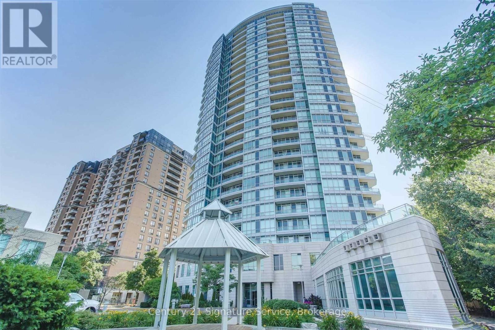 A tall building with a glass facade stands in front of a gazebo.