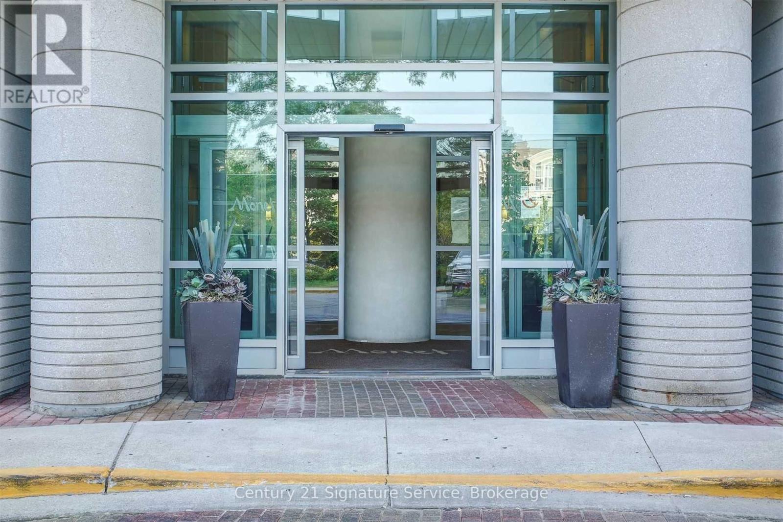 The front of a building with a glass door and two planters on either side.