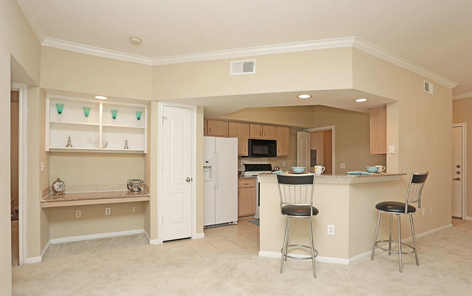 A kitchen with white cabinets and a white fridge.