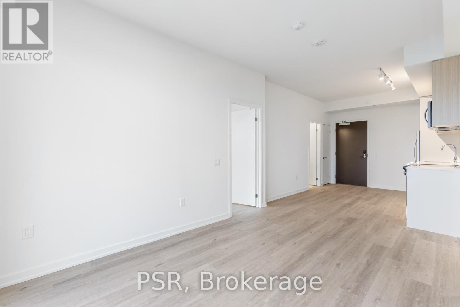 A spacious room with wooden flooring and white walls, labeled "PSR, Brokerage".