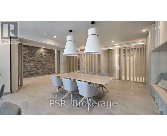 A modern dining room with a stone wall and a long table with chairs.