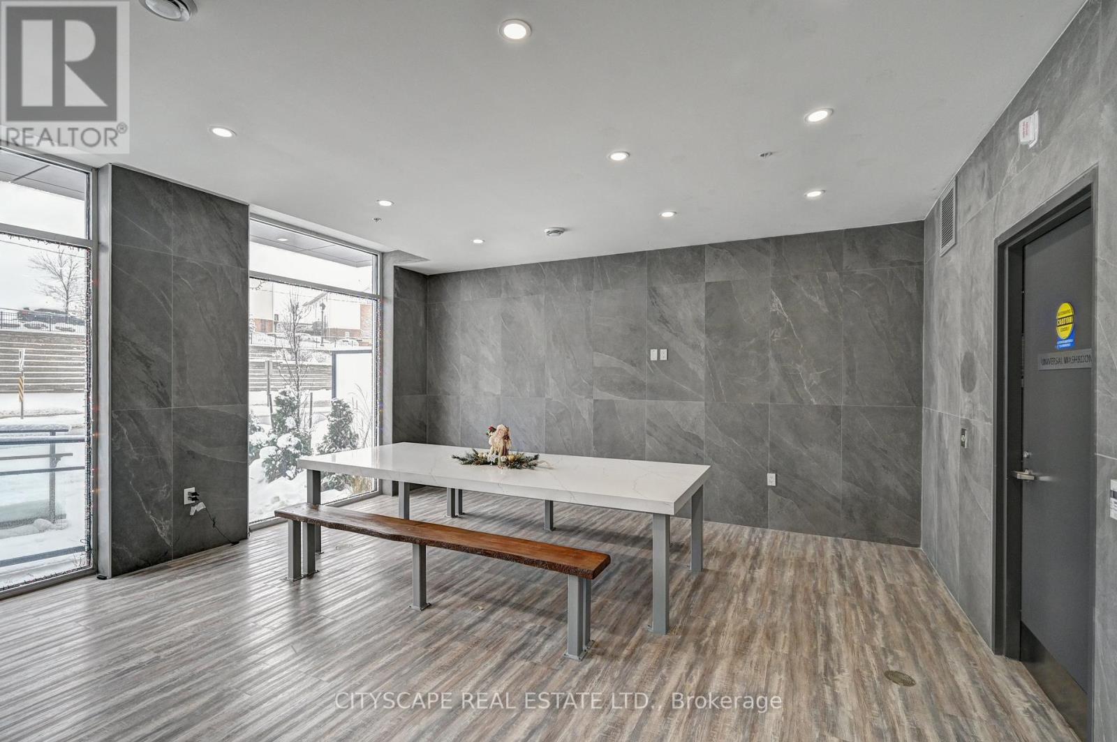 A modern dining room with a marble wall and wooden flooring.
