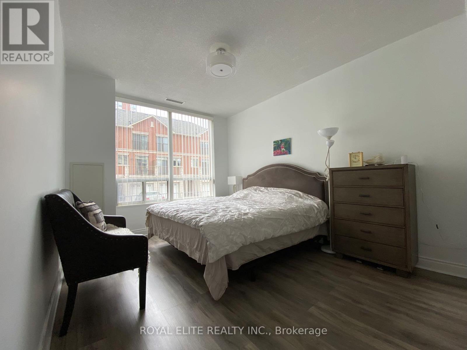 A bedroom with a bed, nightstand, and chair.