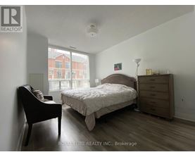 A bedroom with a bed, nightstand, and chair.
