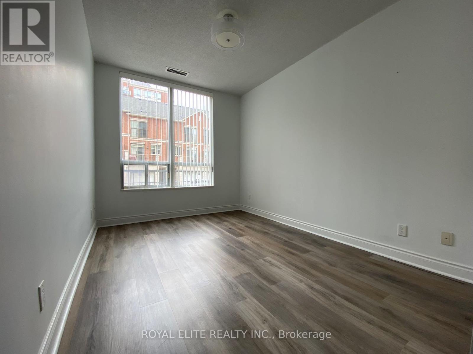 A room with wooden flooring and a window showing a view of a building.