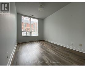 A room with wooden flooring and a window showing a view of a building.