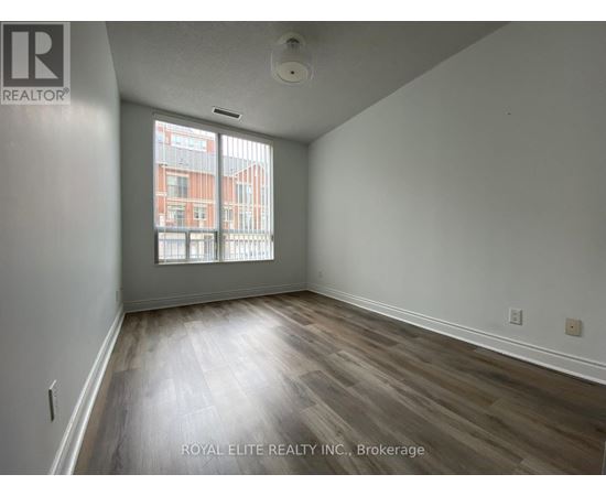 A room with wooden flooring and a window showing a view of a building.