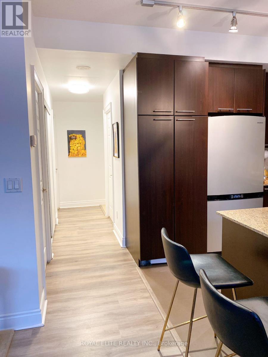 A kitchen area with a white fridge, brown cabinets and a white door.