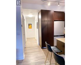 A kitchen area with a white fridge, brown cabinets and a white door.