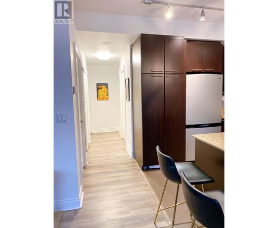 A kitchen area with a white fridge, brown cabinets and a white door.