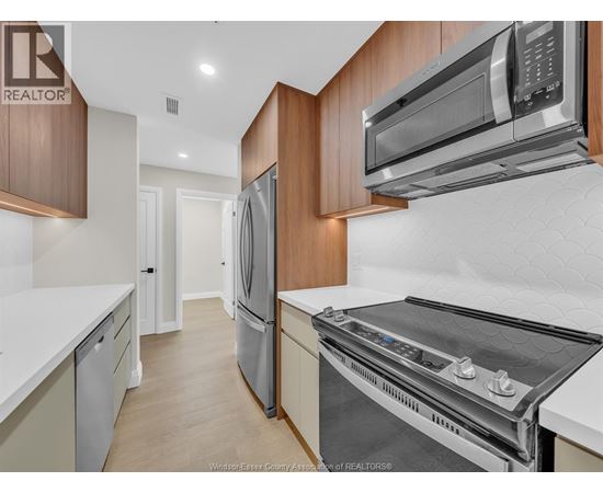 A kitchen with a refrigerator, oven, and microwave.