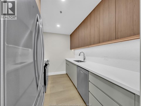 A modern kitchen with a stainless steel refrigerator and a white countertop.