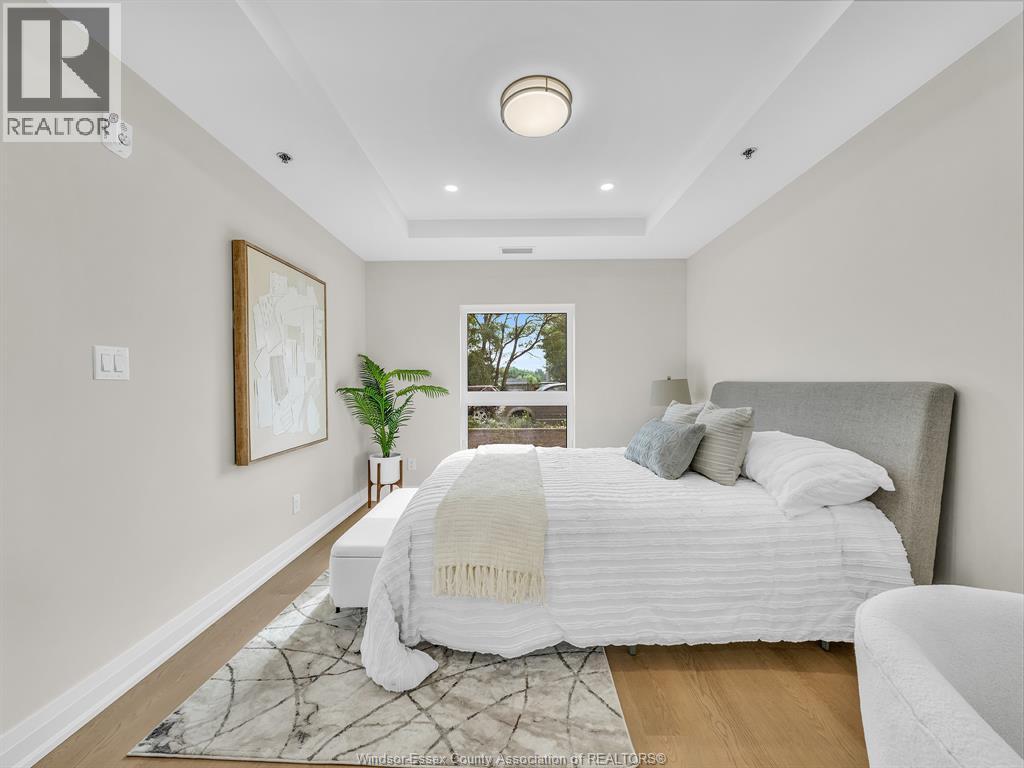 A bedroom with a large bed and a window overlooking trees.