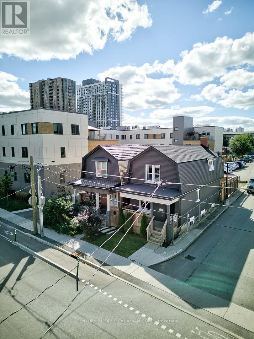 A house with a grey roof is situated in front of a tall building.
